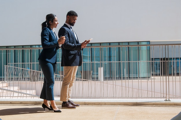 Business people using tablet and standing outdoors