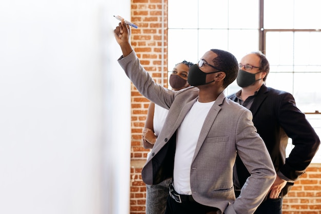 Free photo business people wearing masks brainstorming