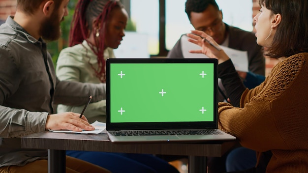 Free photo business people working with paperwork and greenscreen on laptop, planning collaboration. using blank mockup template with chroma key display and copyspace background. close up.