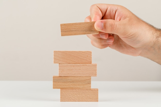 Business planning concept on white backgroud side view. hand placing wooden block on tower.