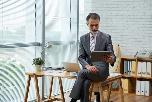 Business professional working with digital tablet in his eco-friendly office seated on the wooden desk