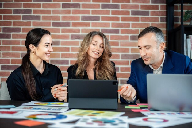 Business session in an office Women and a man discussing business affairs Gadgets and papers