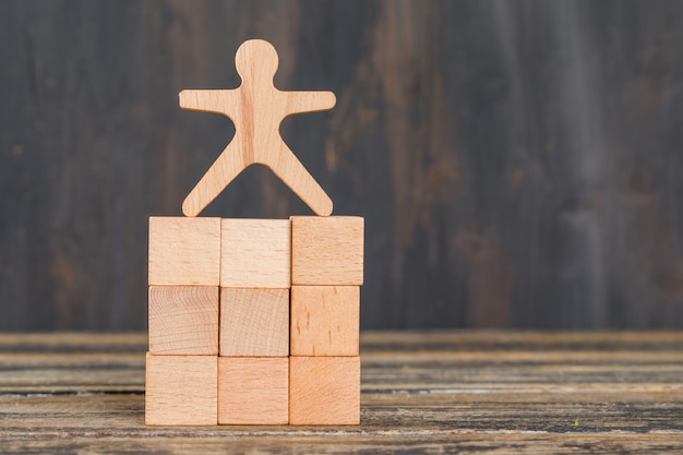 Free photo business success concept with human model on wooden cubes on wooden table side view.