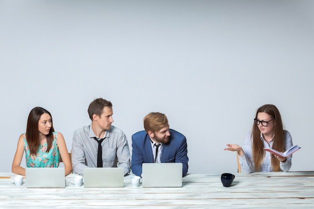 Free photo business team working together at office on light gray background. all working on laptops. boss reading notebook. copyspace image