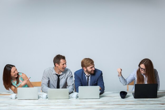 Business team working together at office on light gray background. headmistress threatening, others laughing. copyspace image