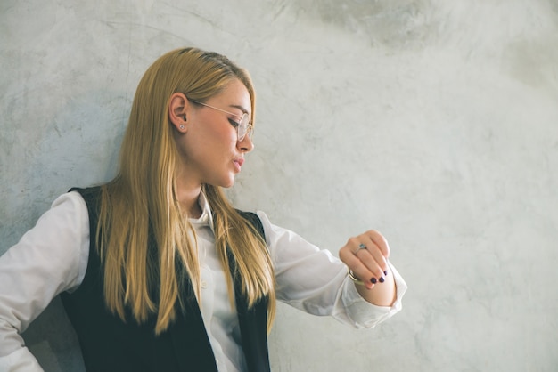 Free photo business and time management concept. young businesswoman looking at wrist watch. time is money