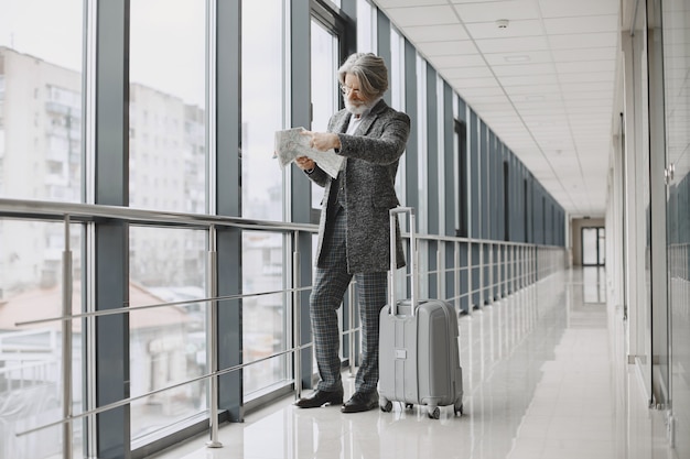 Business trip. Corporate and people concept. Male in a gray coat. Senior with a map.