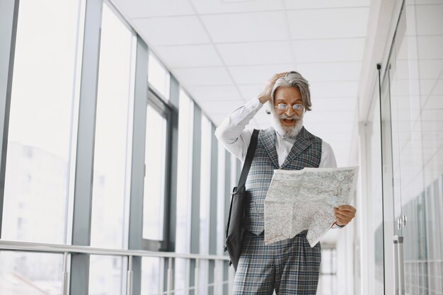 Business trip. Corporate and people concept. Male in a gray coat. Senior with a map.