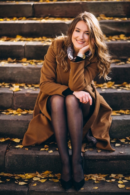 Business woman in coat sitting on the stairs