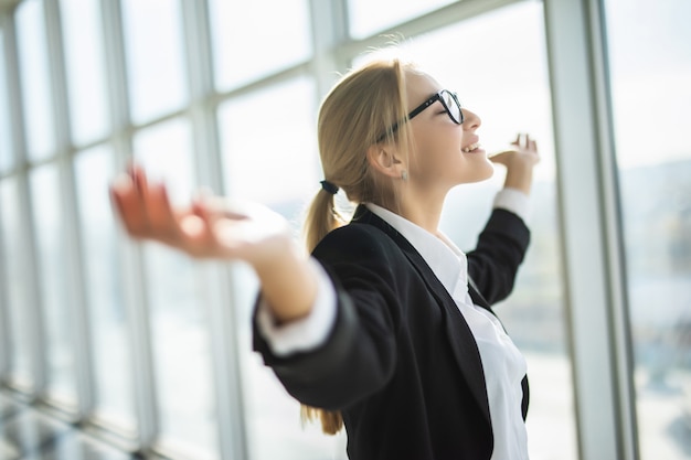 Business woman excited hold hands up raised arms celebrate victory in modern office