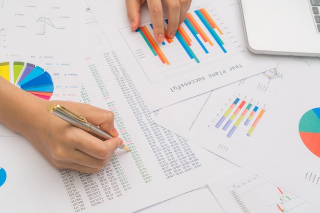 Free photo business woman hand  with financial charts  and laptop on the ta