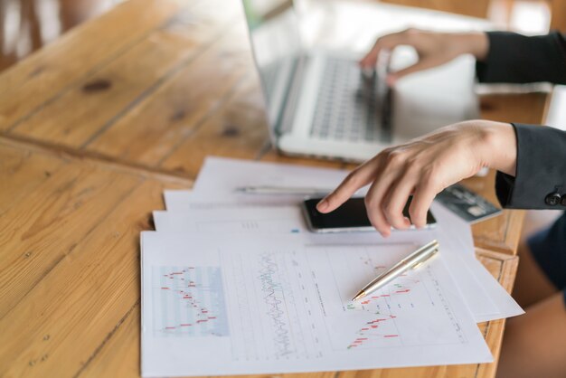 Business woman hand with Financial charts and laptop on the table .