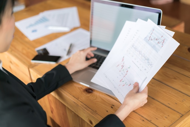 Free photo business woman hand with financial charts and laptop on the table .