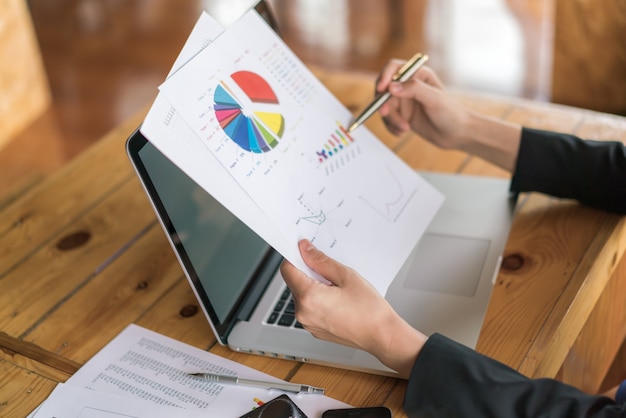 Business woman hand with Financial charts and laptop on the table .