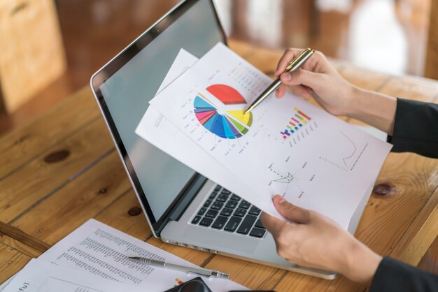 Business woman hand with Financial charts and laptop on the table .