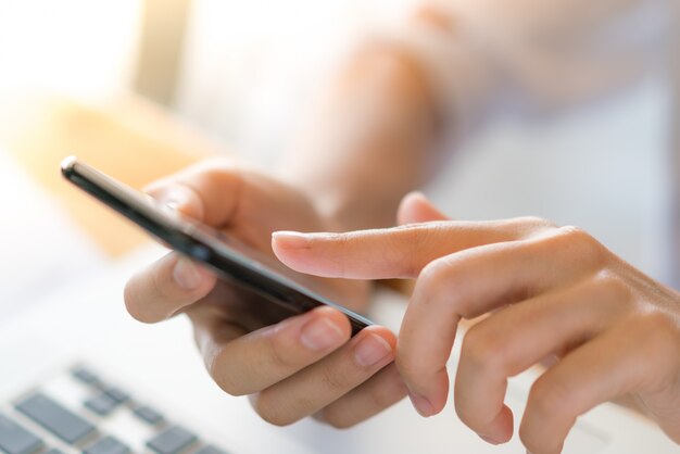 Business woman hand with Financial charts and mobile phone over laptop on the table .