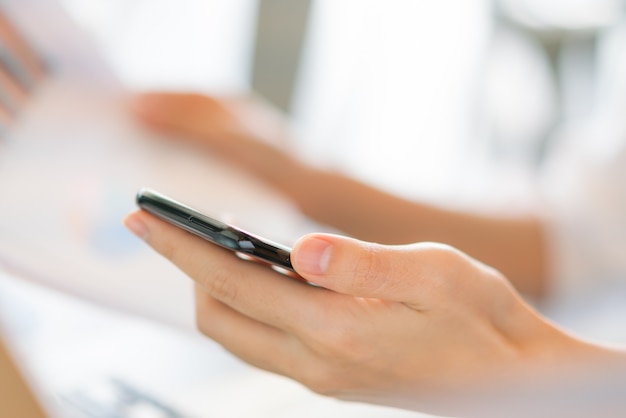 Business woman hand with Financial charts and mobile phone over laptop on the table .