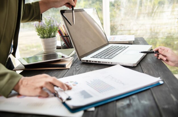 Business woman hands using laptop computer placed on messy office desktop.