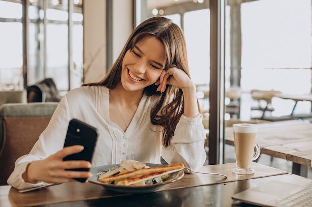 Business woman having lunch in a cafe and working on computer