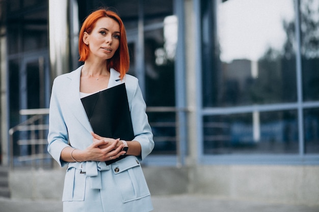 Free Photo business woman holding folder by the office center