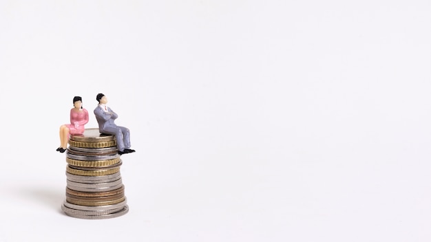 Free photo business woman and man sitting on a pile of coins copy space