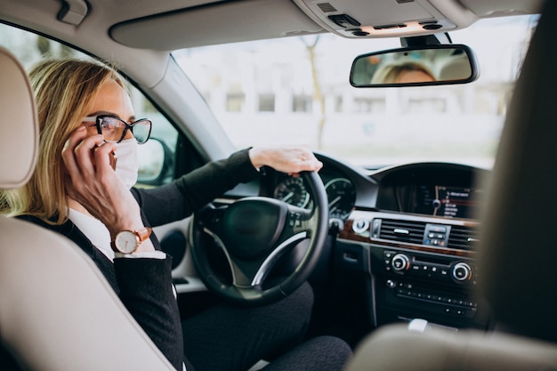 Business woman in protection mask sitting inside a car