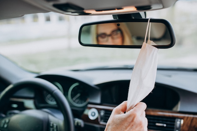 Free photo business woman in protection mask sitting inside a car