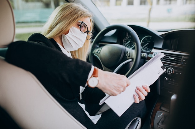 Free photo business woman in protection mask sitting inside a car