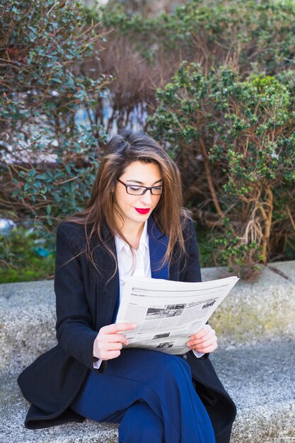 Business woman reading newspaper outside 