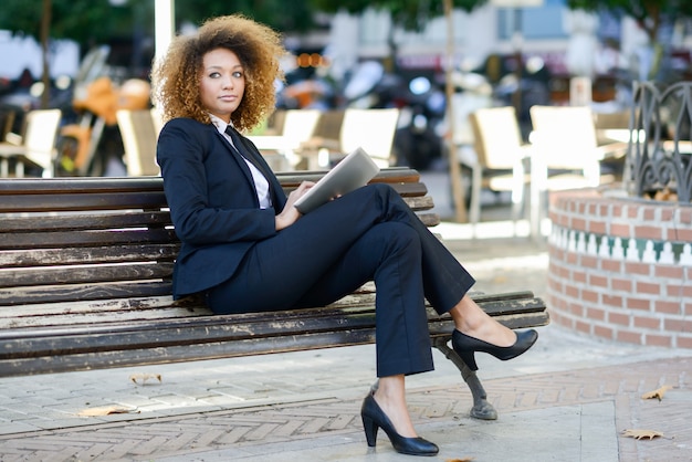 Free photo business woman sitting on a bench with a tablet