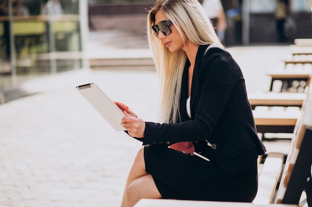 Free Photo business woman sitting on bench and working on tablet