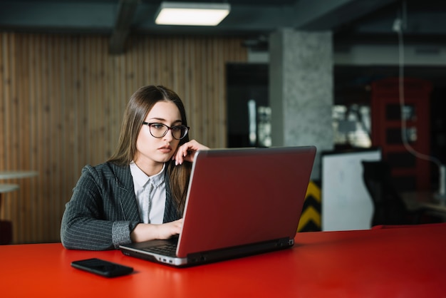 Business woman in suit using laptop at table