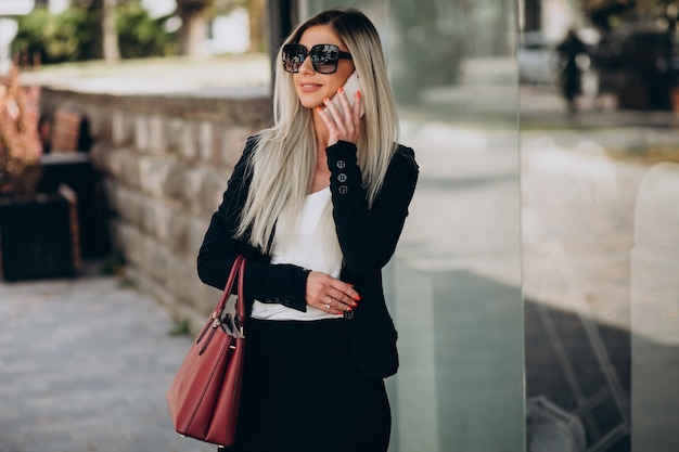 Free photo business woman talking on the phone in the street