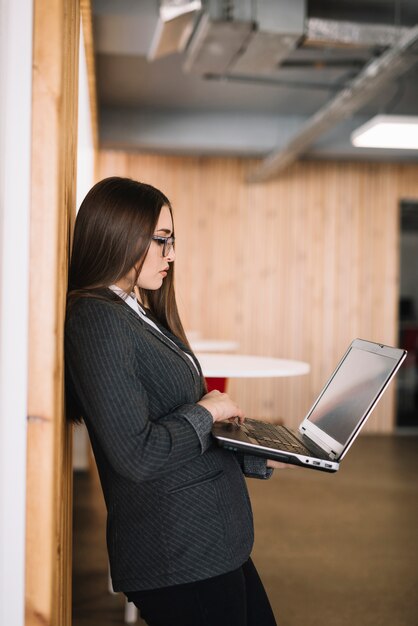 Business woman typing on laptop keyboard at wall