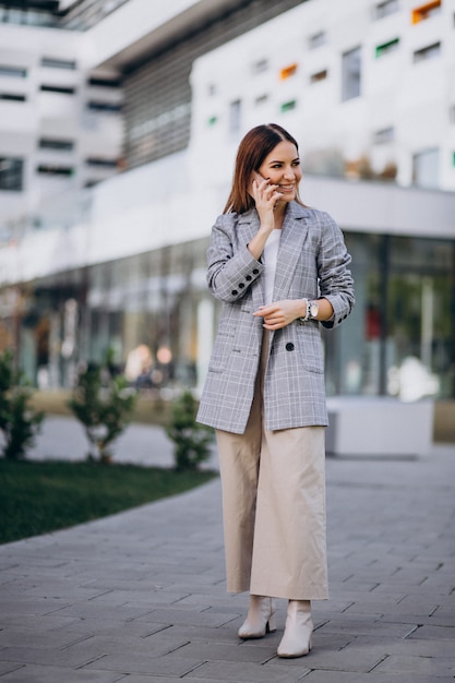 Business woman using phone outside in the street by the building