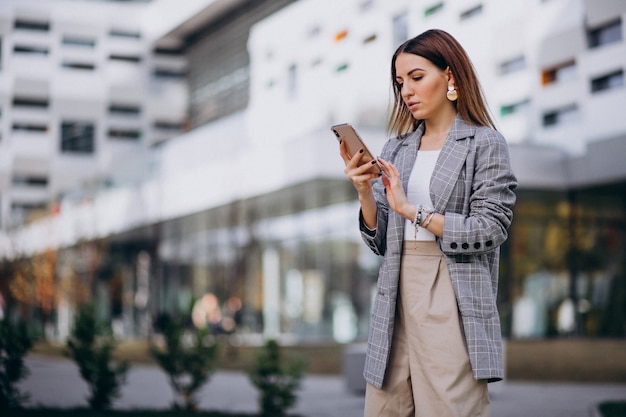 Business woman using phone outside in the street by the building