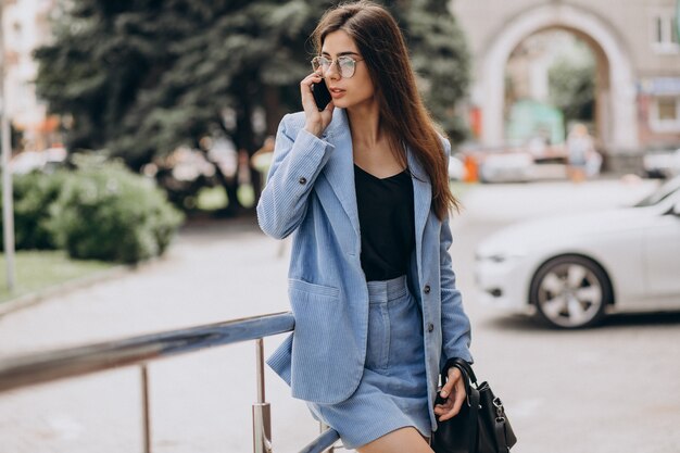 Business woman using phone outside the street