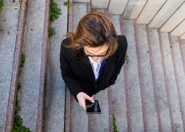 Free photo business woman using smartphone on stairs