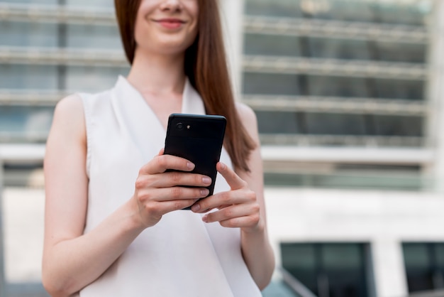 Business woman using smartphone in the street