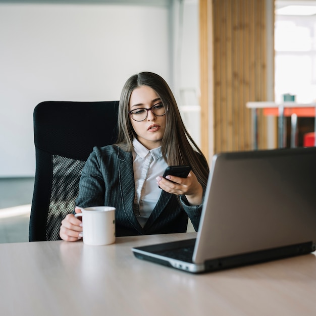 Business woman using smartphone at table