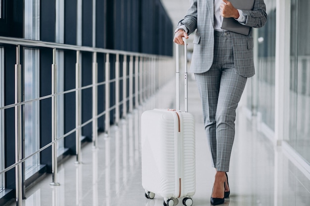 Free photo business woman with travel luggage in airport, holding laptop