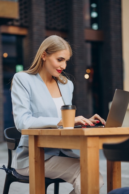 Free photo business woman working on computer in a cafe and drinking coffee