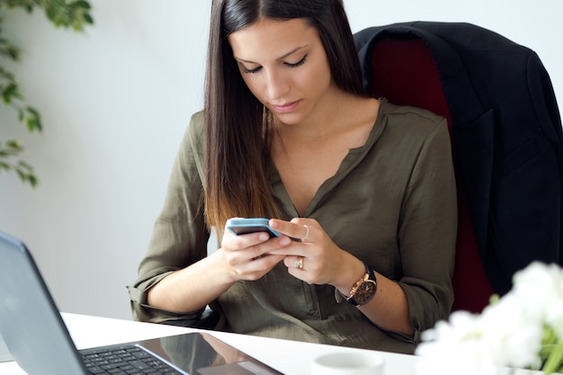 Business woman working with mobile phone in her office.