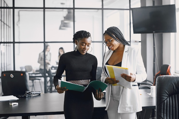 Business women talking near the desk during a coffee break in the hallway of the big corporation