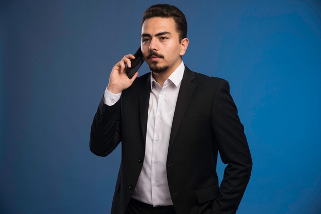 Businessman in black suit talking to the phone.