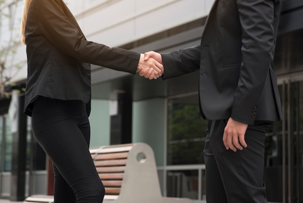 Free photo businessman and businesswoman are shaking hands in front of the office building