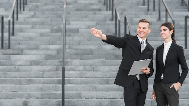 Businessman and businesswoman pointing somewhere