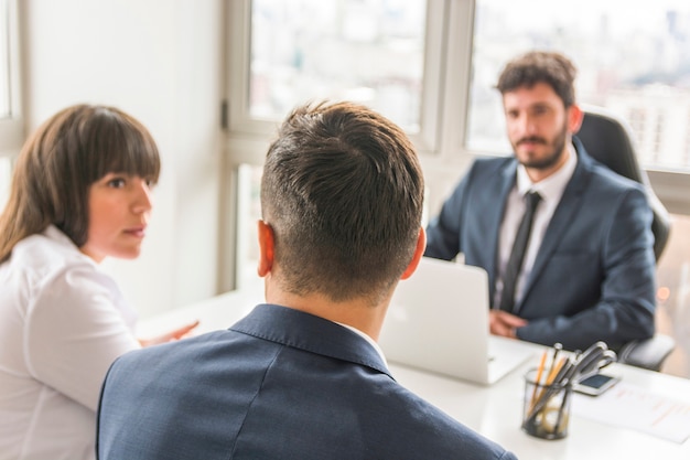 Free photo businessman and businesswoman sitting in front of manager at workplace