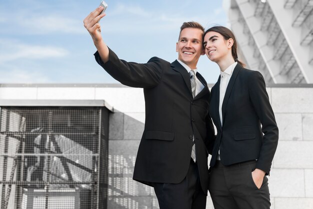 Businessman and businesswoman taking selfie