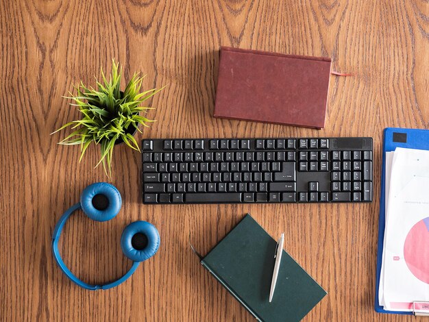 Free photo businessman desktop concept image top view, clipboard, books, headphones, pot of grass